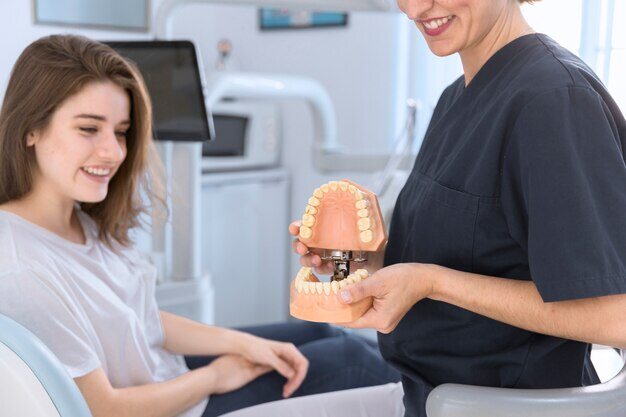 close-up-dentist-showing-teeth-model-smiling-patient_23-2147879173