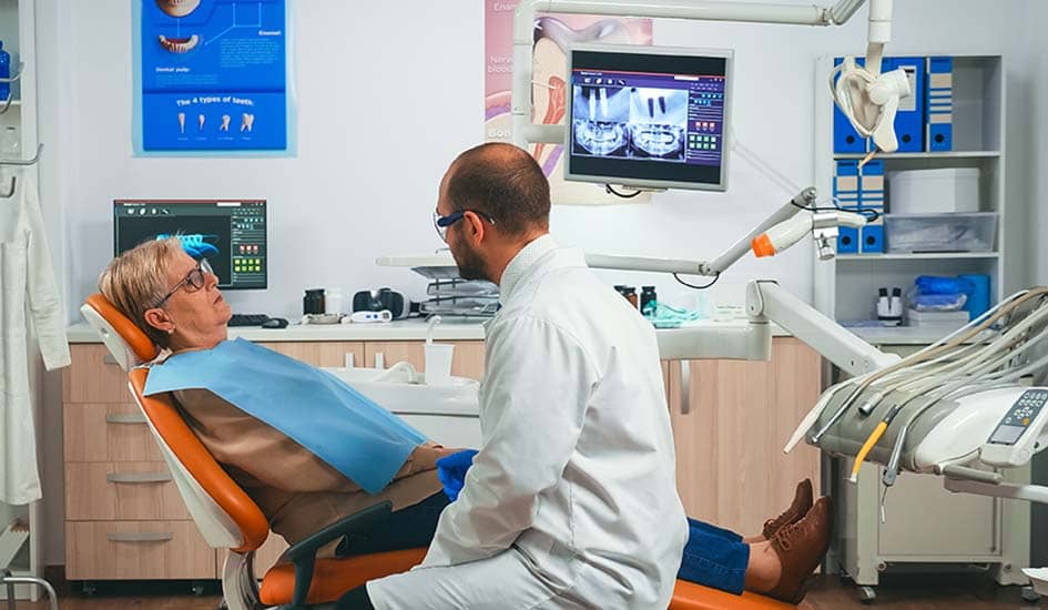 orthodontist-discusses-an-mri-scan-with-patient-dental-care-oral-health-dentist-and-old-woman