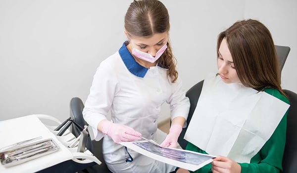 young-dentist-talking-with-female-patient-dental-clinic-preparing-treatment-examining-x-ray-image-dentistry