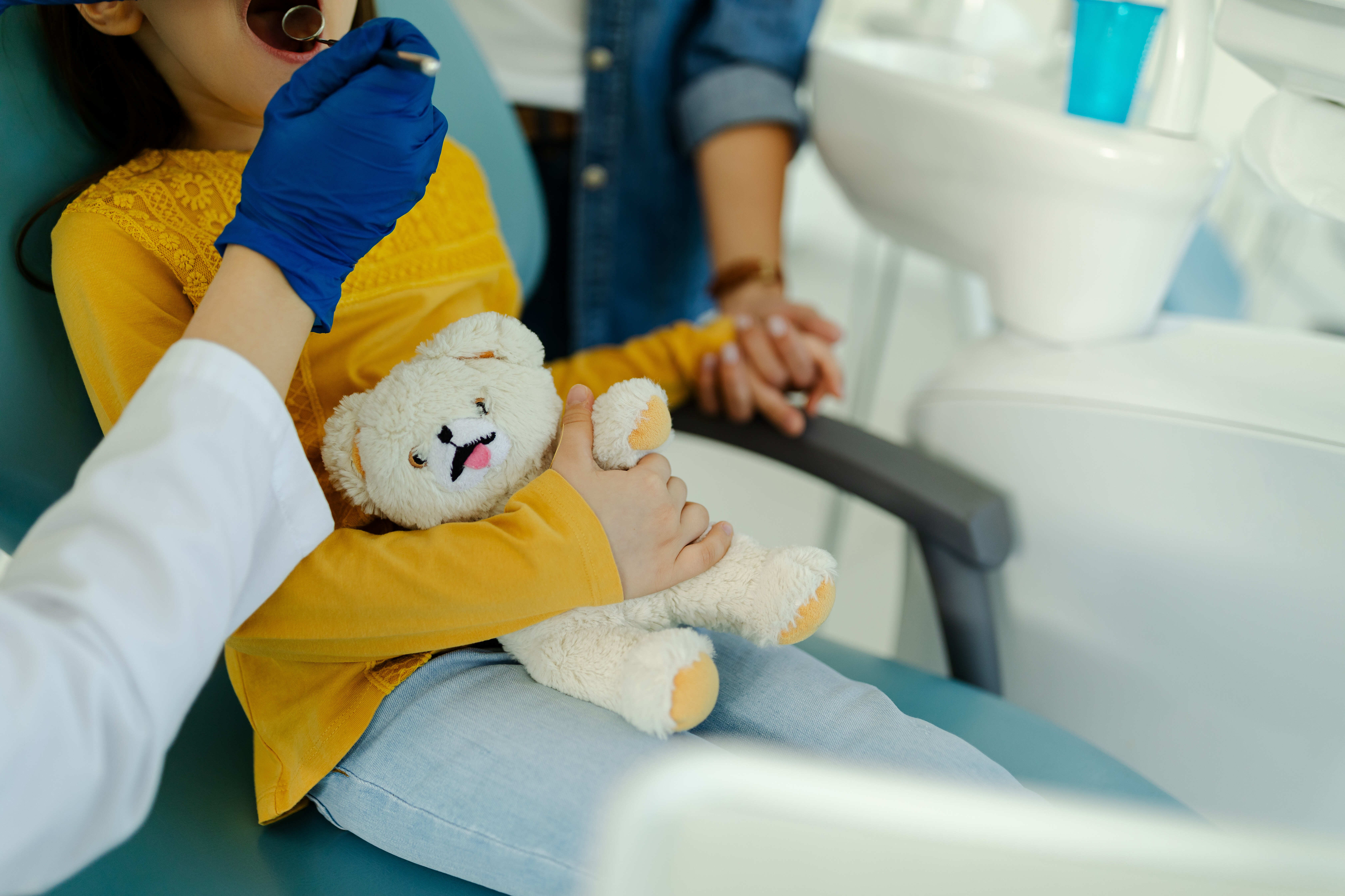 Mother holding the hand of her daughter who is visiting the dentist and thus supporting her