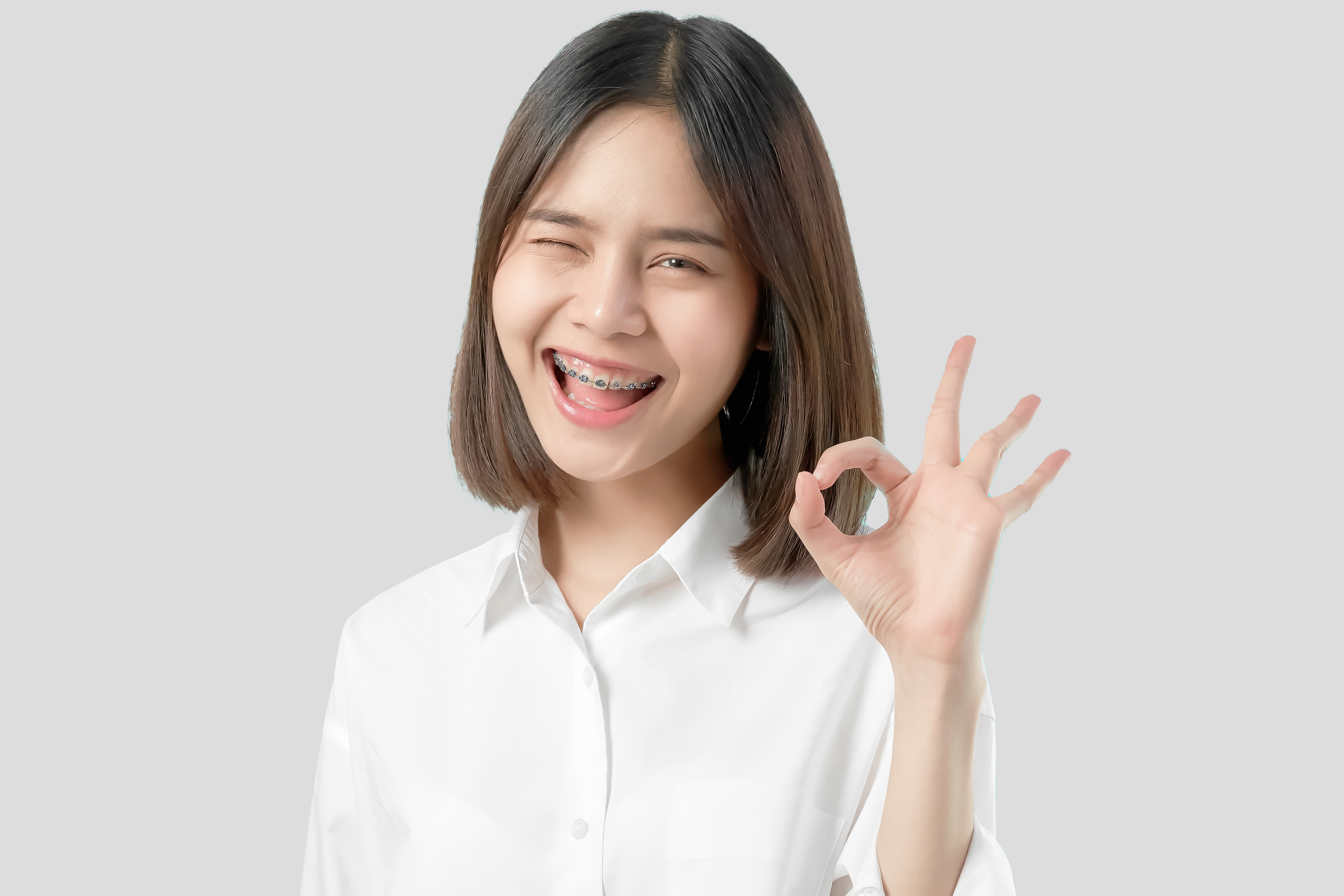 portrait-happily-asian-woman-shows-ok-sign-braces-smiling-witch-looking-camera copy