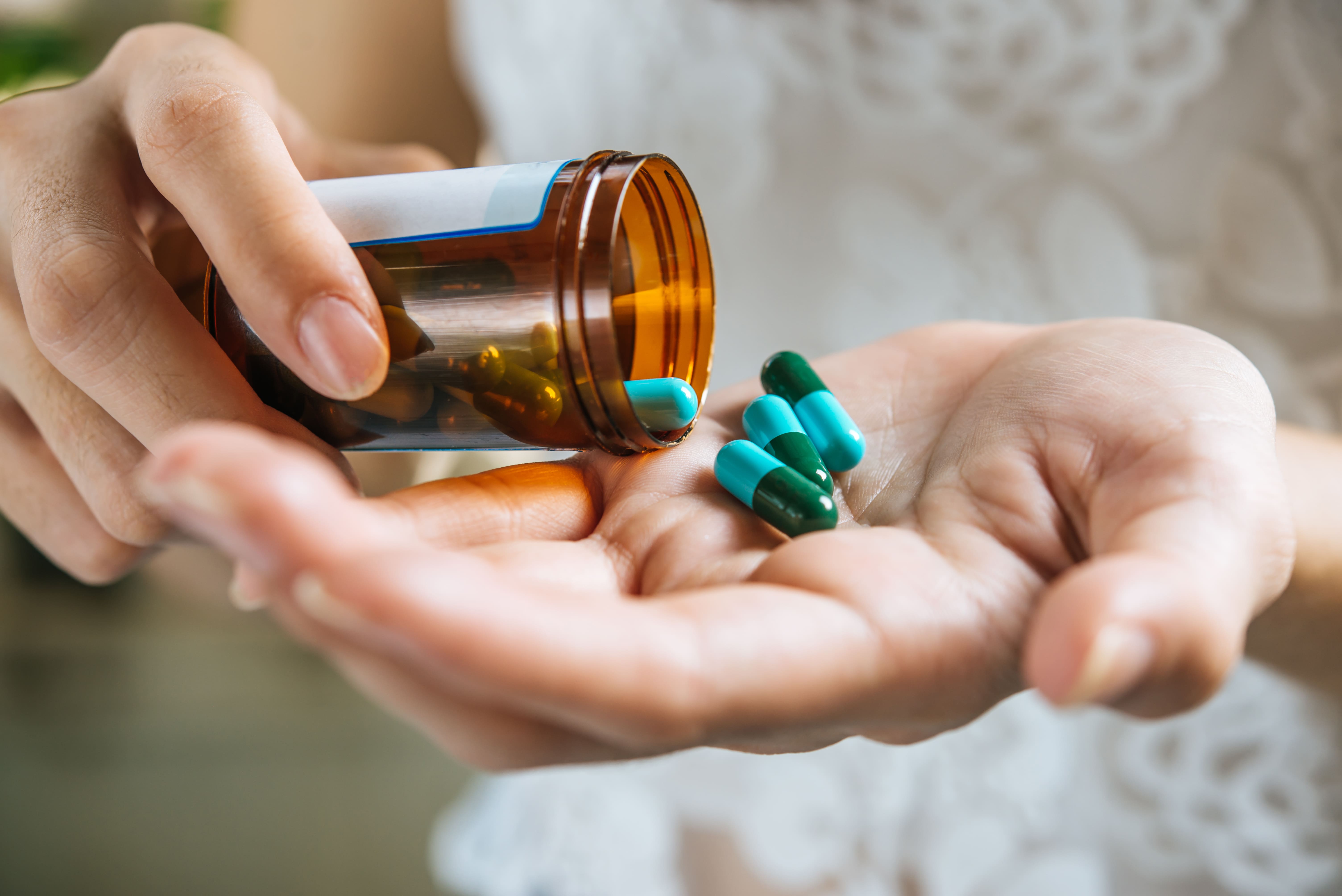 woman-s-hand-pours-medicine-pills-out-bottle (1)